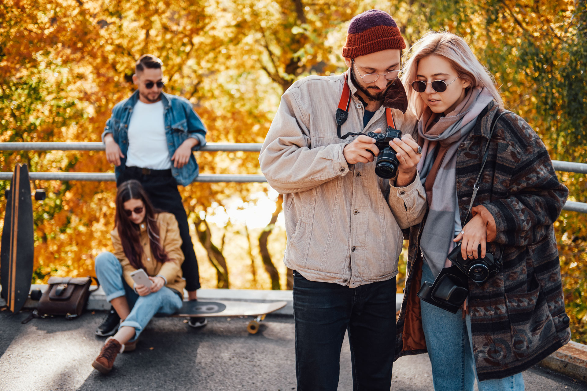 Company of friends relaxing and photographing in autumn park