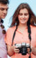 Five friends in a half circle, smiling, looking at the camera in the girl's hands